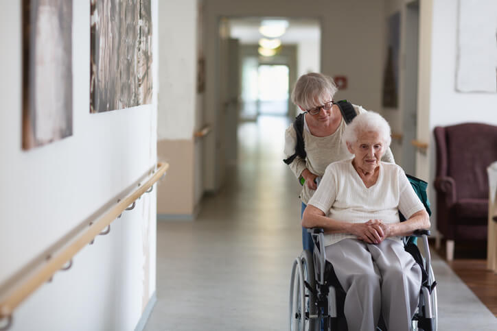 Older woman in a wheelchair being pushed by daughter