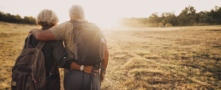 Elderly couple hiking on a hill while looking at the sunrise