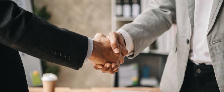 Two businessmen in suits shaking hands after a successful business transaction occured