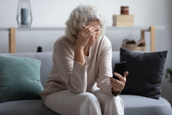 Unhappy stressed mature middle aged woman looking at phone screen